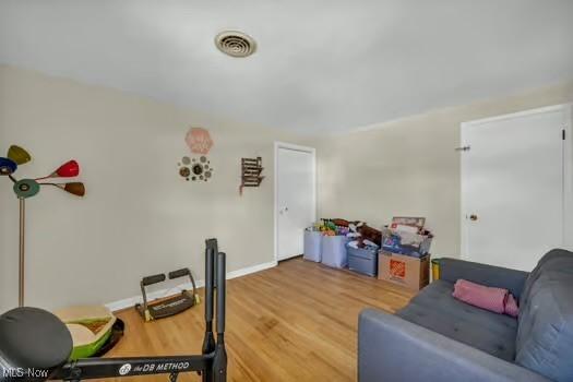 living room featuring baseboards, wood finished floors, and visible vents