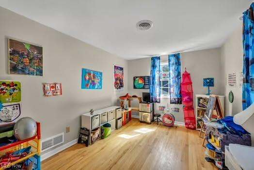 playroom featuring baseboards, wood finished floors, and visible vents