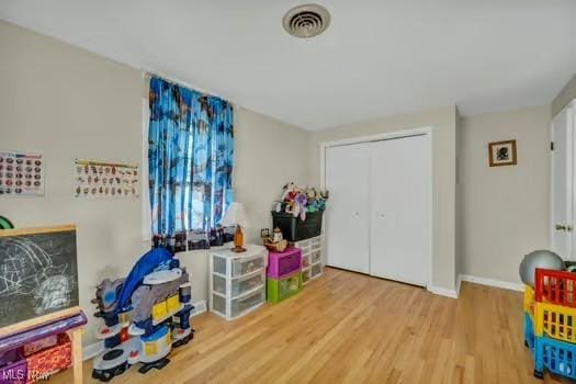 playroom featuring baseboards, wood finished floors, and visible vents