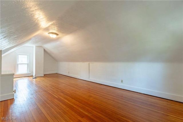 bonus room with baseboards, a textured ceiling, hardwood / wood-style floors, and lofted ceiling