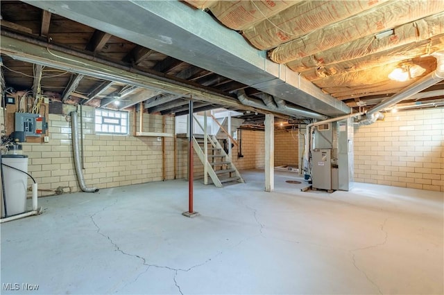 basement featuring stairs, heating unit, and electric panel