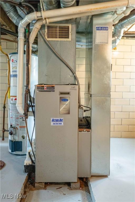 utility room with visible vents and water heater