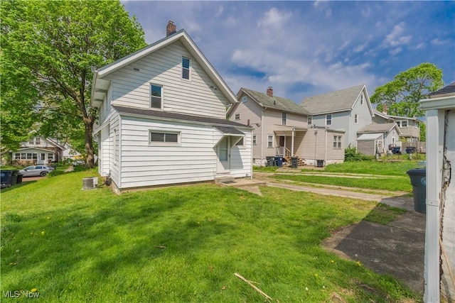 back of property with a yard, a chimney, and cooling unit