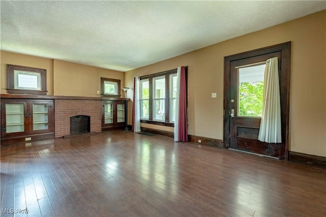 unfurnished living room with baseboards, a textured ceiling, wood finished floors, and a fireplace