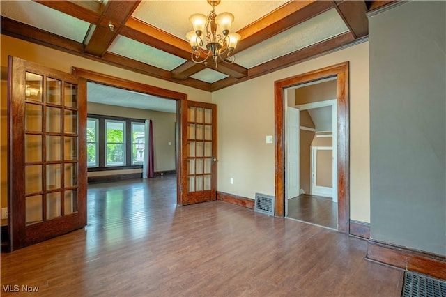 unfurnished room with visible vents, wood finished floors, a chandelier, french doors, and coffered ceiling