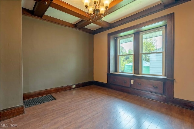 spare room featuring an inviting chandelier, visible vents, beamed ceiling, hardwood / wood-style flooring, and coffered ceiling