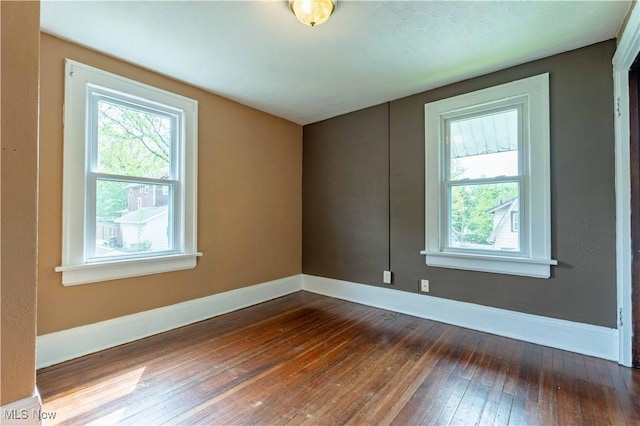 additional living space featuring baseboards and dark wood-style floors