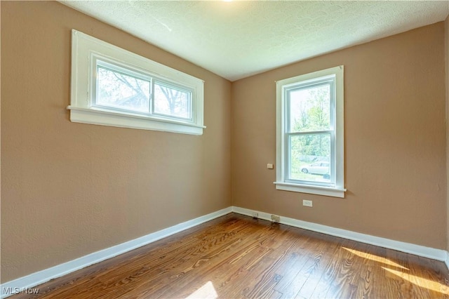 empty room featuring baseboards, wood finished floors, and a healthy amount of sunlight