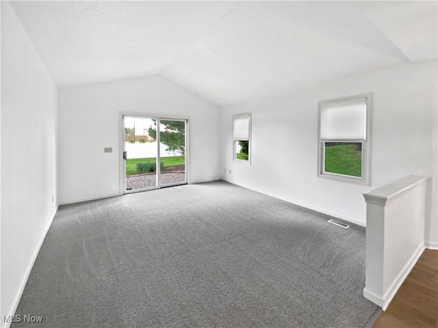 carpeted spare room with baseboards, vaulted ceiling, and visible vents