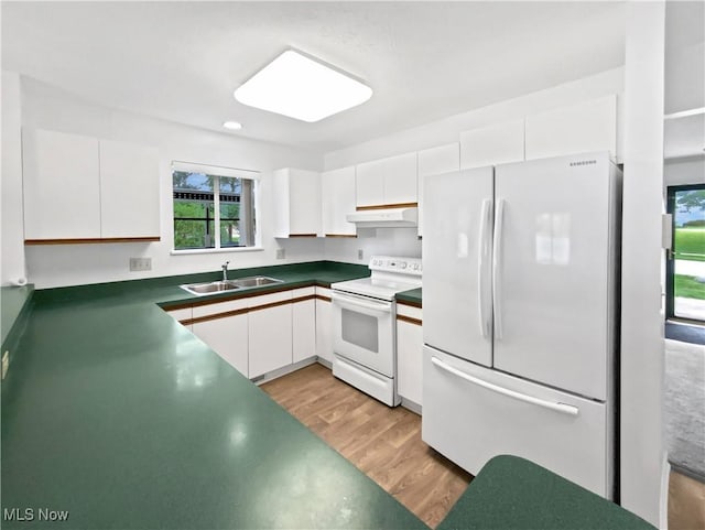 kitchen with a sink, under cabinet range hood, white appliances, and a healthy amount of sunlight
