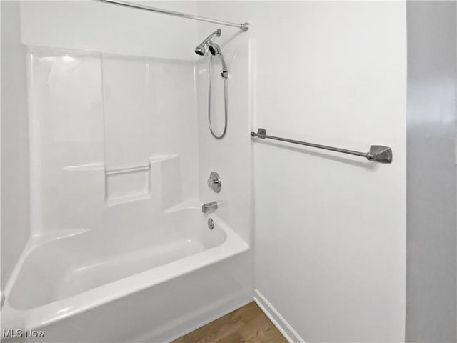 bathroom with baseboards, shower / washtub combination, and wood finished floors