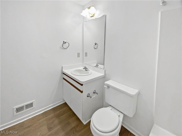 bathroom featuring vanity, toilet, wood finished floors, and visible vents