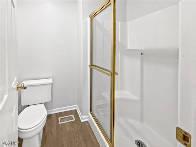 bathroom featuring visible vents, a shower stall, wood finished floors, baseboards, and toilet