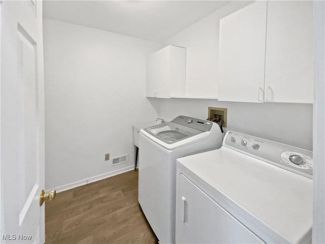 laundry area with visible vents, cabinet space, baseboards, dark wood-style floors, and washer and clothes dryer