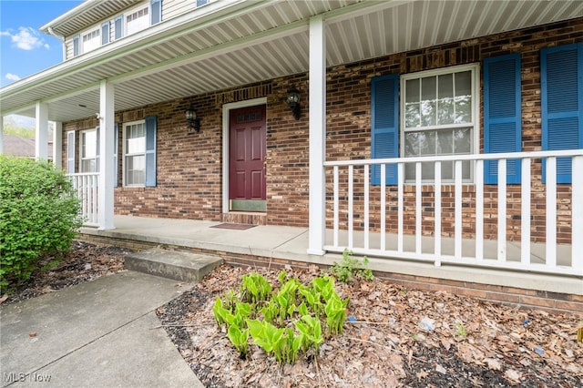 property entrance featuring brick siding and covered porch