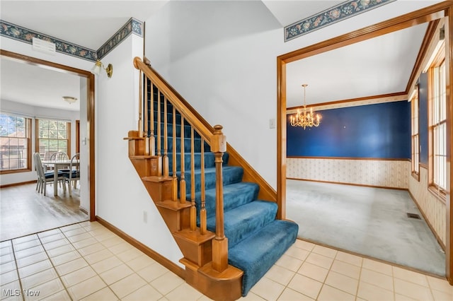 stairs with an inviting chandelier, visible vents, baseboards, wallpapered walls, and carpet