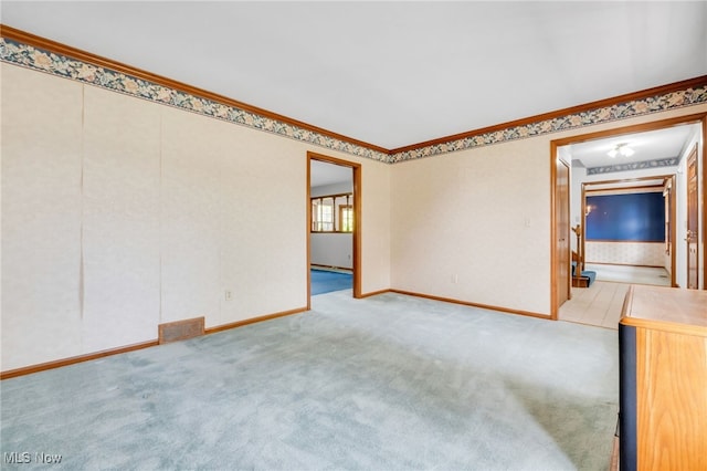 unfurnished room featuring baseboards, visible vents, ornamental molding, and light carpet