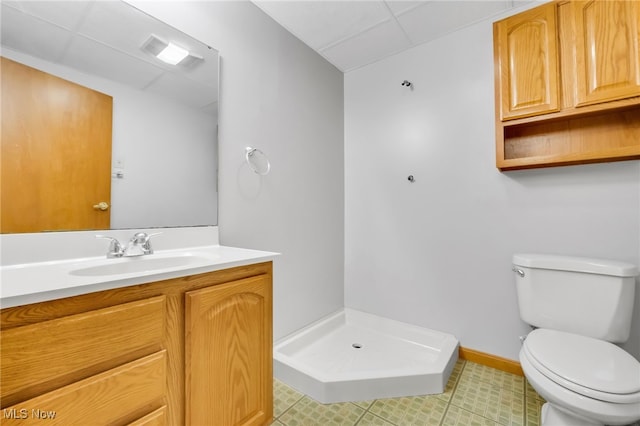 bathroom featuring a paneled ceiling, a stall shower, vanity, baseboards, and toilet