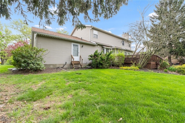 back of house featuring entry steps, a chimney, a yard, and a deck