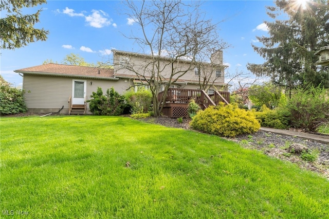 back of house featuring a lawn, a wooden deck, entry steps, and a chimney