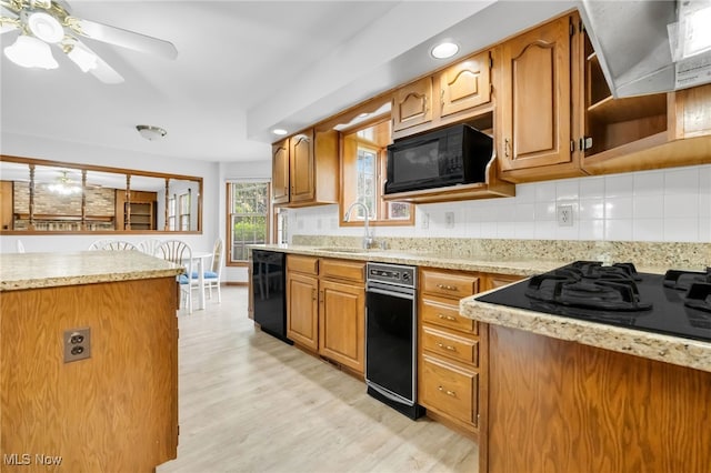 kitchen featuring backsplash, light wood finished floors, a sink, and black appliances
