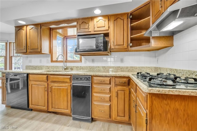 kitchen with plenty of natural light, a sink, black appliances, under cabinet range hood, and light wood-style flooring