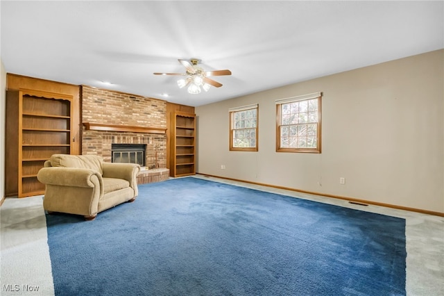 carpeted living room featuring built in features, baseboards, a ceiling fan, and a brick fireplace