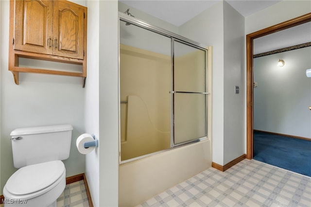 bathroom featuring toilet, baseboards, and shower / bath combination with glass door