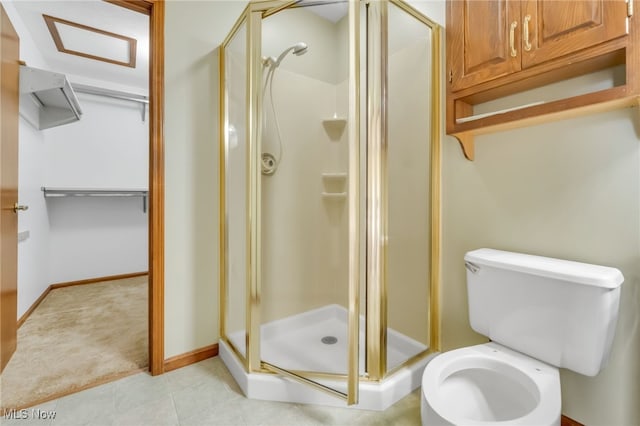 bathroom featuring tile patterned flooring, baseboards, toilet, and a shower stall