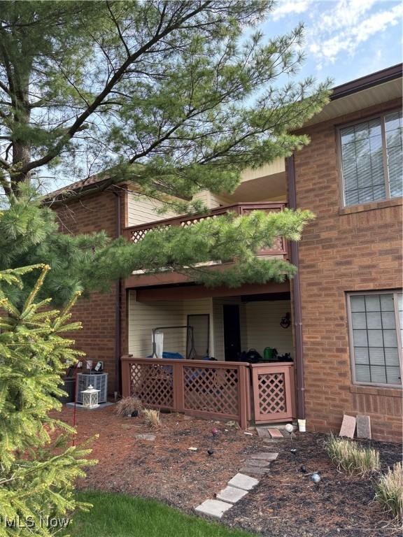 rear view of property featuring brick siding and central AC