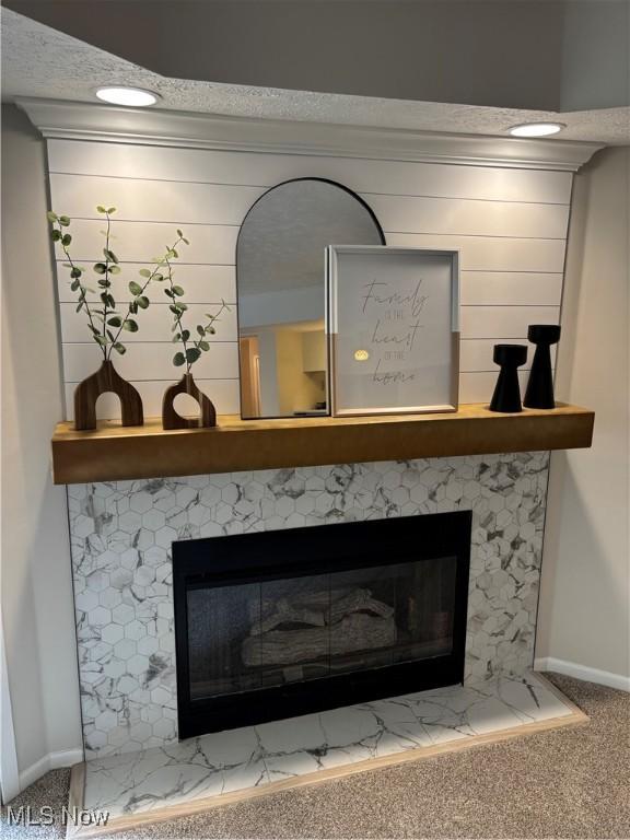 room details with a glass covered fireplace, baseboards, and carpet