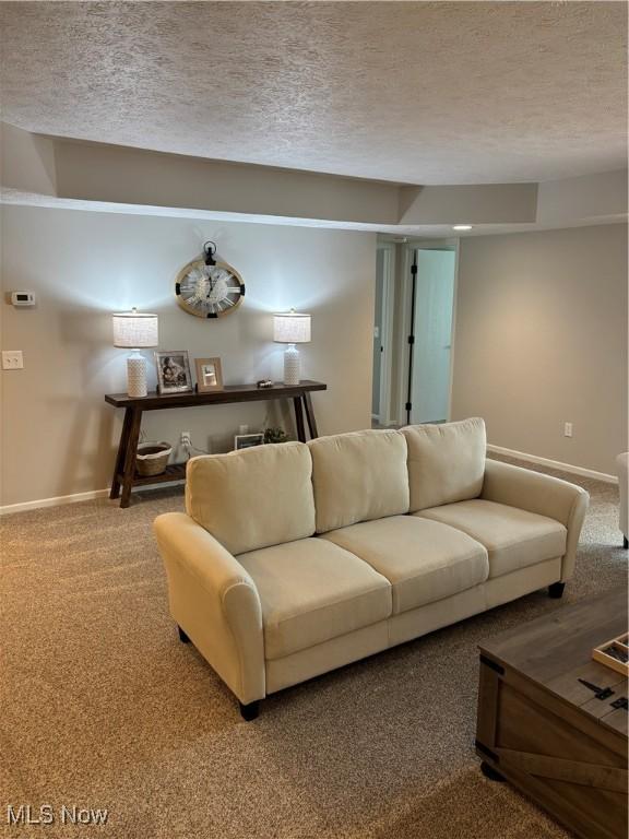 carpeted living area featuring baseboards and a textured ceiling