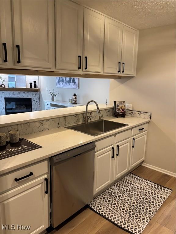 kitchen with light countertops, a sink, light wood-style flooring, and dishwasher