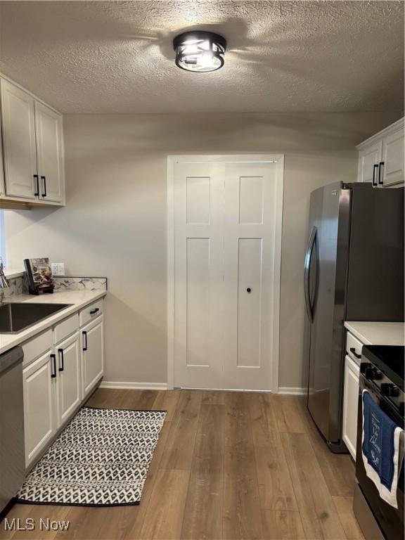 kitchen featuring range with electric stovetop, light countertops, a sink, light wood finished floors, and dishwasher