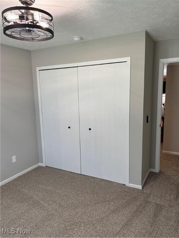 unfurnished bedroom with a closet, baseboards, and carpet flooring
