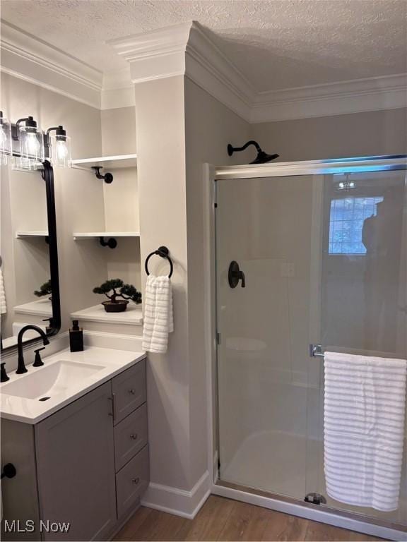 full bathroom with ornamental molding, a textured ceiling, wood finished floors, and a shower stall