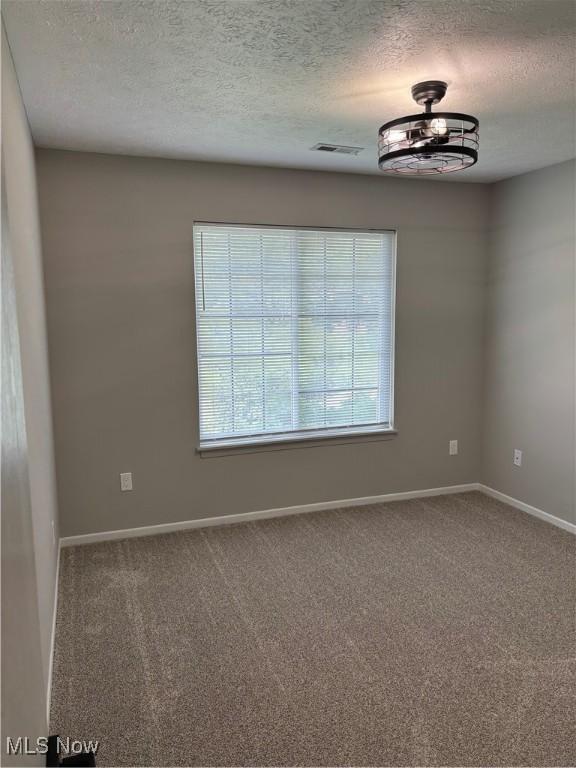unfurnished room featuring carpet floors, a textured ceiling, visible vents, and baseboards