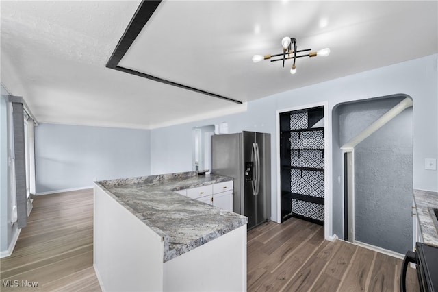 kitchen featuring stainless steel fridge with ice dispenser, a peninsula, baseboards, white cabinetry, and wood finished floors