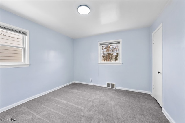 spare room featuring carpet flooring, baseboards, and visible vents