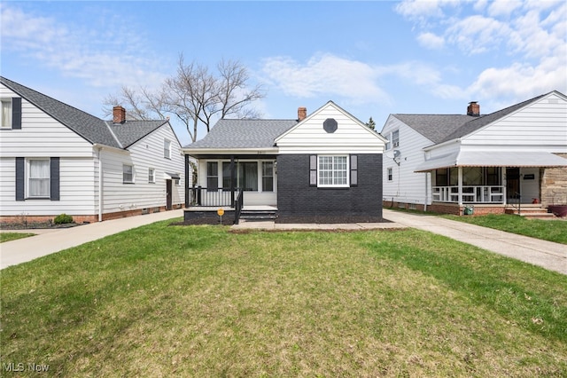 bungalow-style house with a chimney, a sunroom, and a front lawn