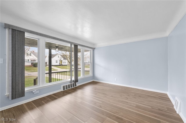 empty room with baseboards, wood finished floors, and visible vents