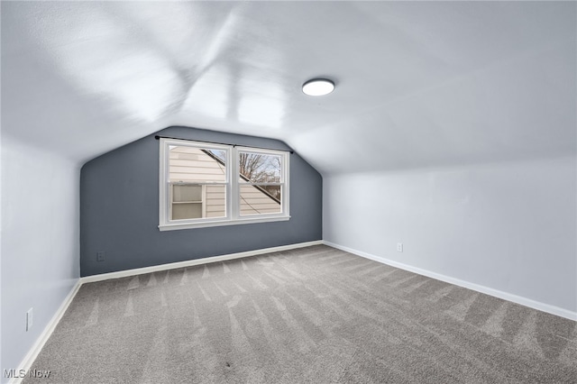 additional living space with baseboards, lofted ceiling, and carpet
