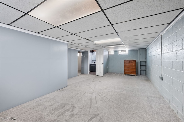basement featuring carpet, a paneled ceiling, and concrete block wall