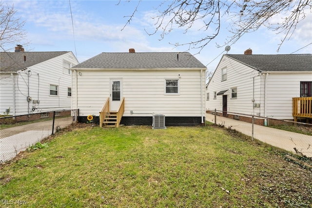 rear view of house featuring entry steps, fence, central air condition unit, and a lawn