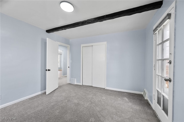 unfurnished bedroom featuring baseboards, multiple windows, carpet, and beam ceiling