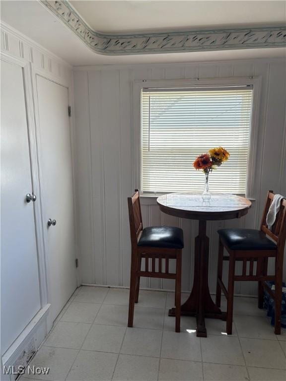 dining space featuring light tile patterned floors and a decorative wall