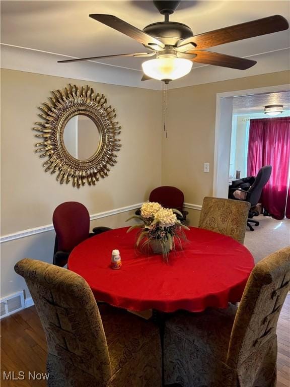 dining space with visible vents, a ceiling fan, and wood finished floors