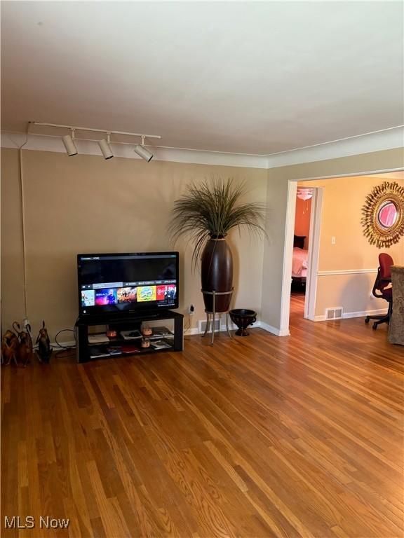 living area with visible vents, wood finished floors, and track lighting