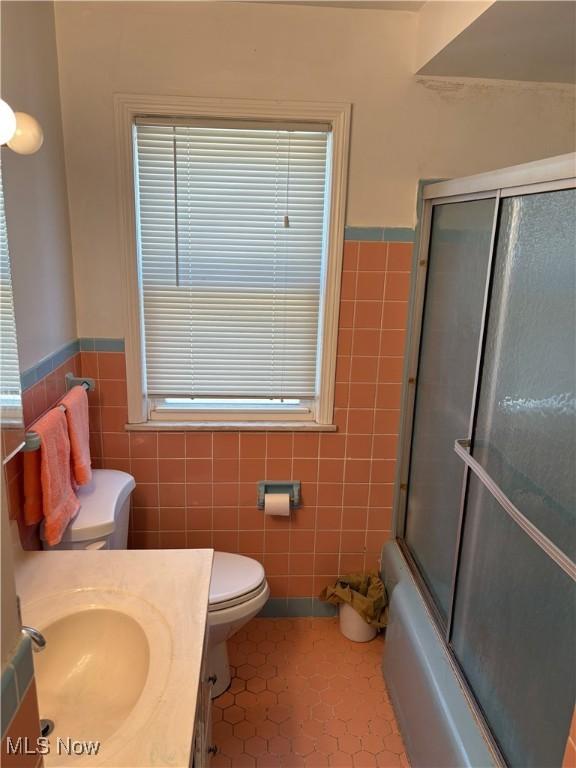 4218 Eastway Rd, South Euclid, OH 44121 - bathroom with tile patterned flooring, wainscoting, toilet, and tile walls