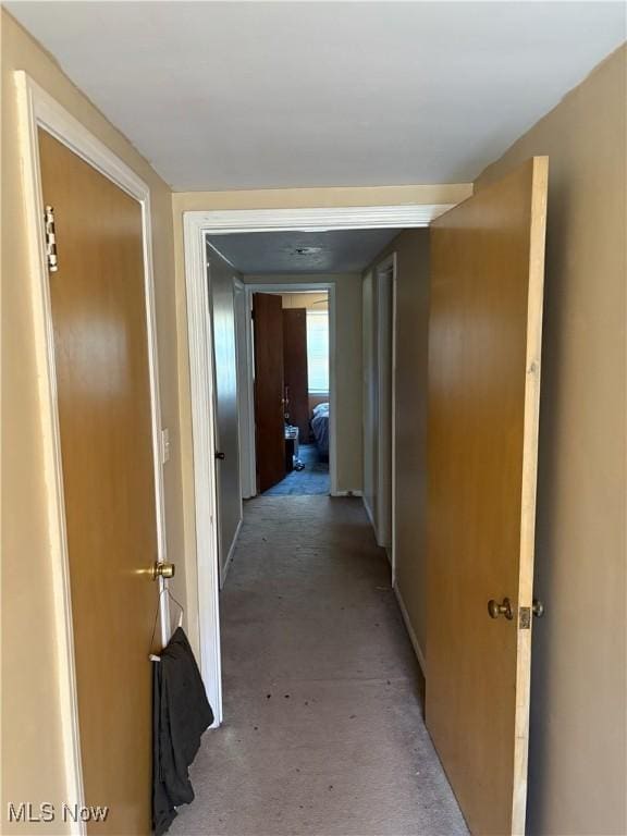 hall with baseboards and light carpet